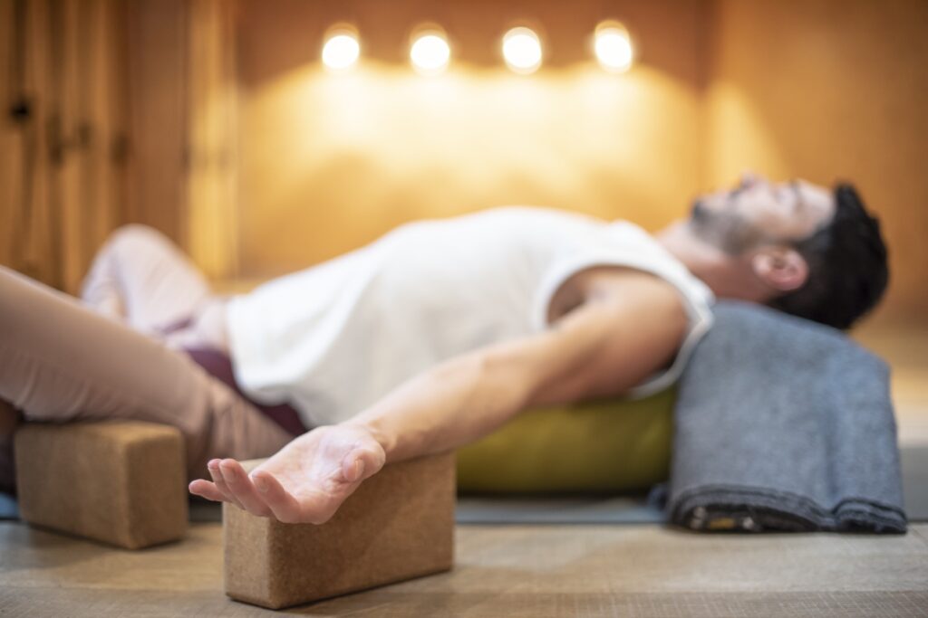 Posture de yoga restauratif avec appui des mains et coussin, pratique calme et relaxante.